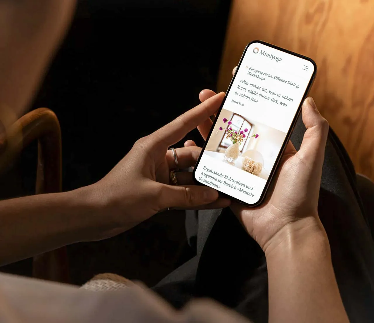 Person hält Smartphone mit geöffneter Mindyoga-Webseite und Zitat von Henry Ford.