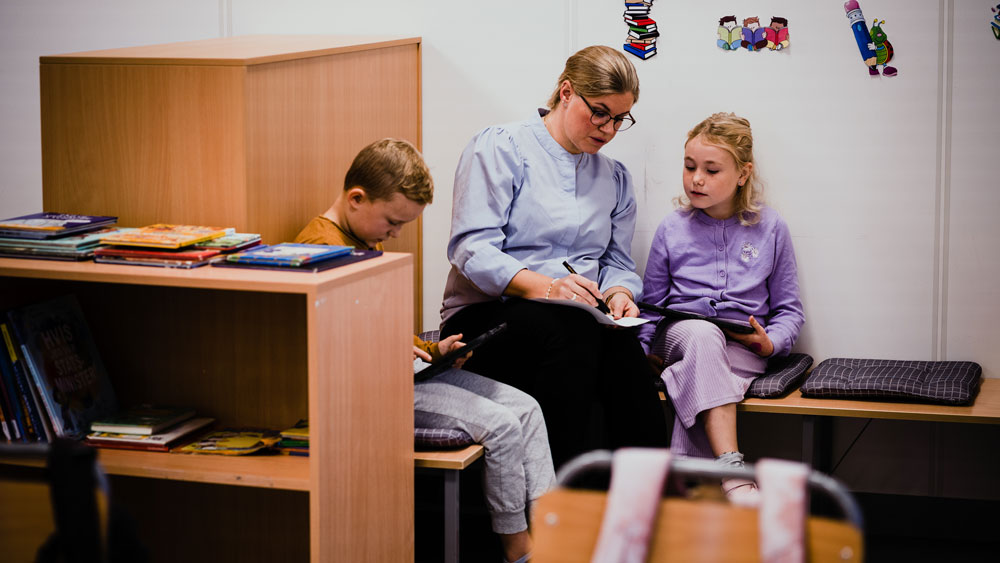 Lærer i klasserommet sammen med to elever, fotografi