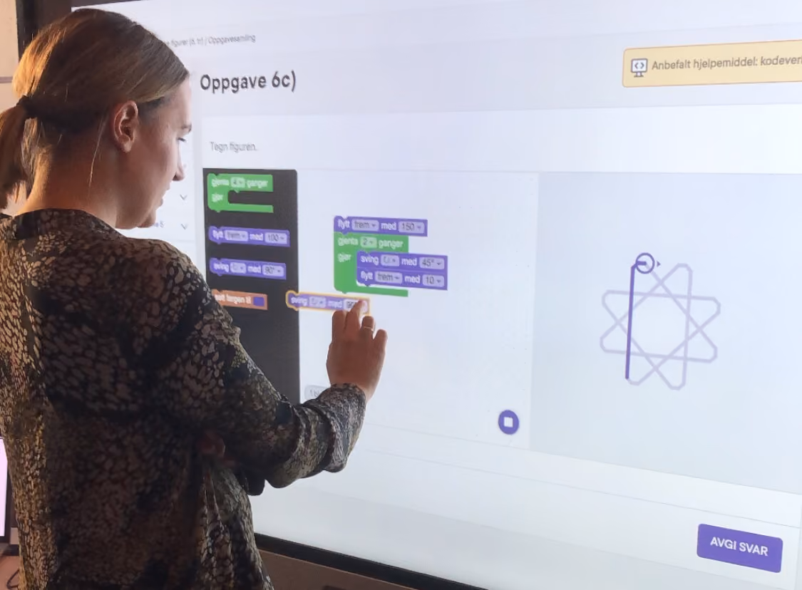 Bilde av en lærer som løser en programmeringsoppgave på en digital tavle.