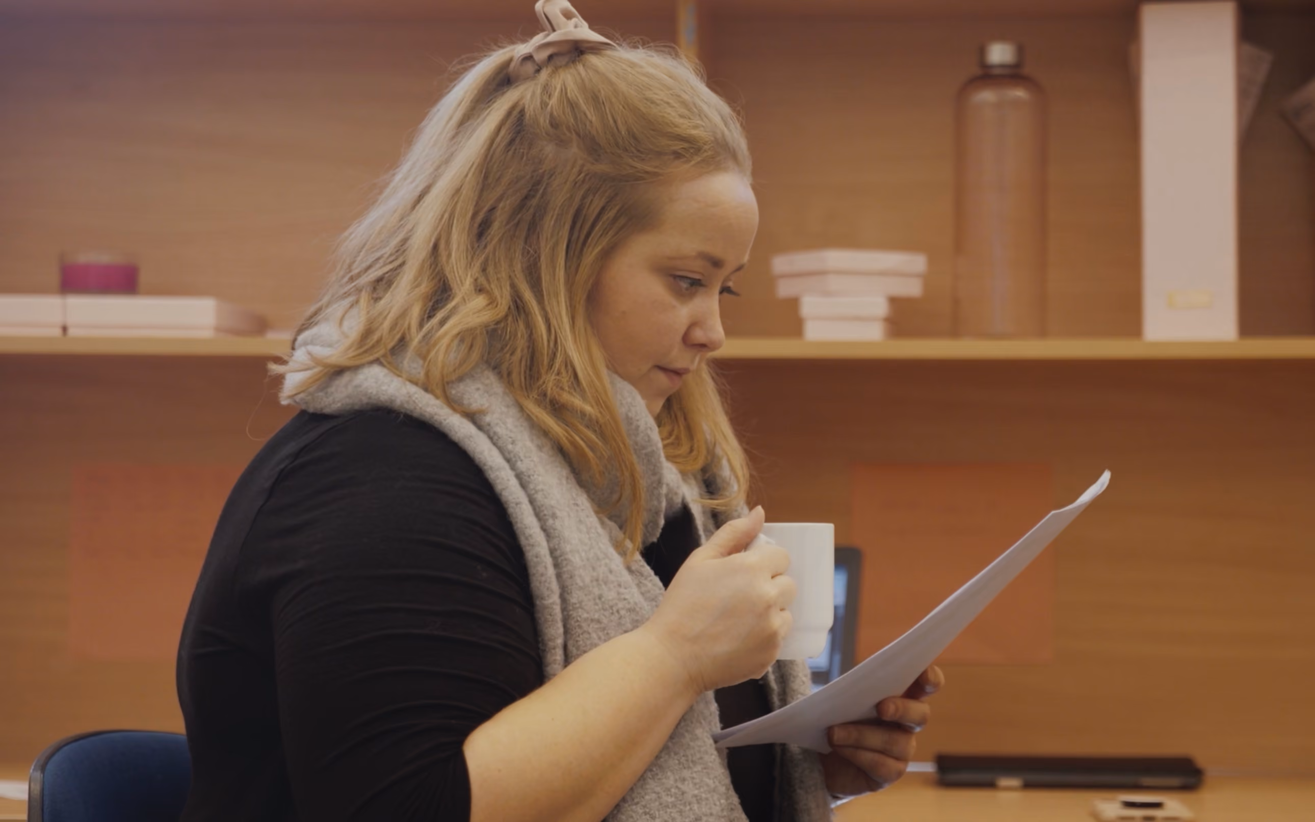 Matematikklærer som holder en kaffekopp og ser på en plan som er skrevet ut.