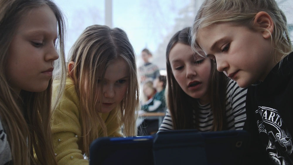 Fire skolebarn som arbeider sammen på en ipad, fotografi