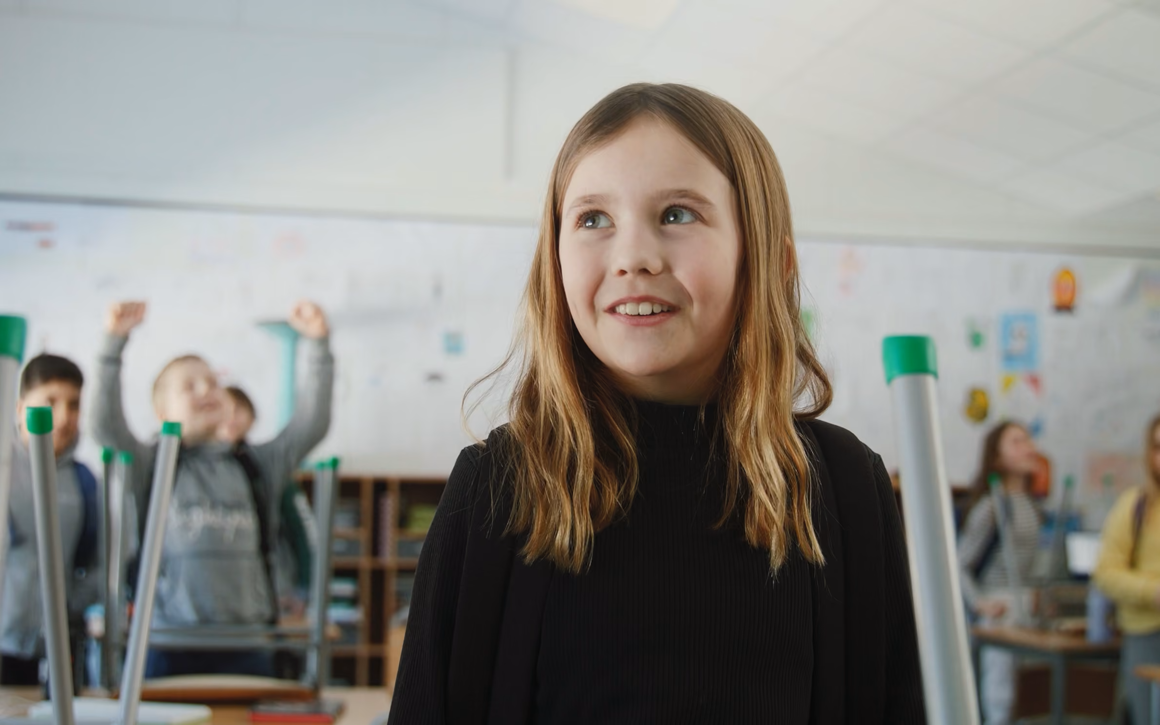 Smilende elev står ved siden av pulten sin.