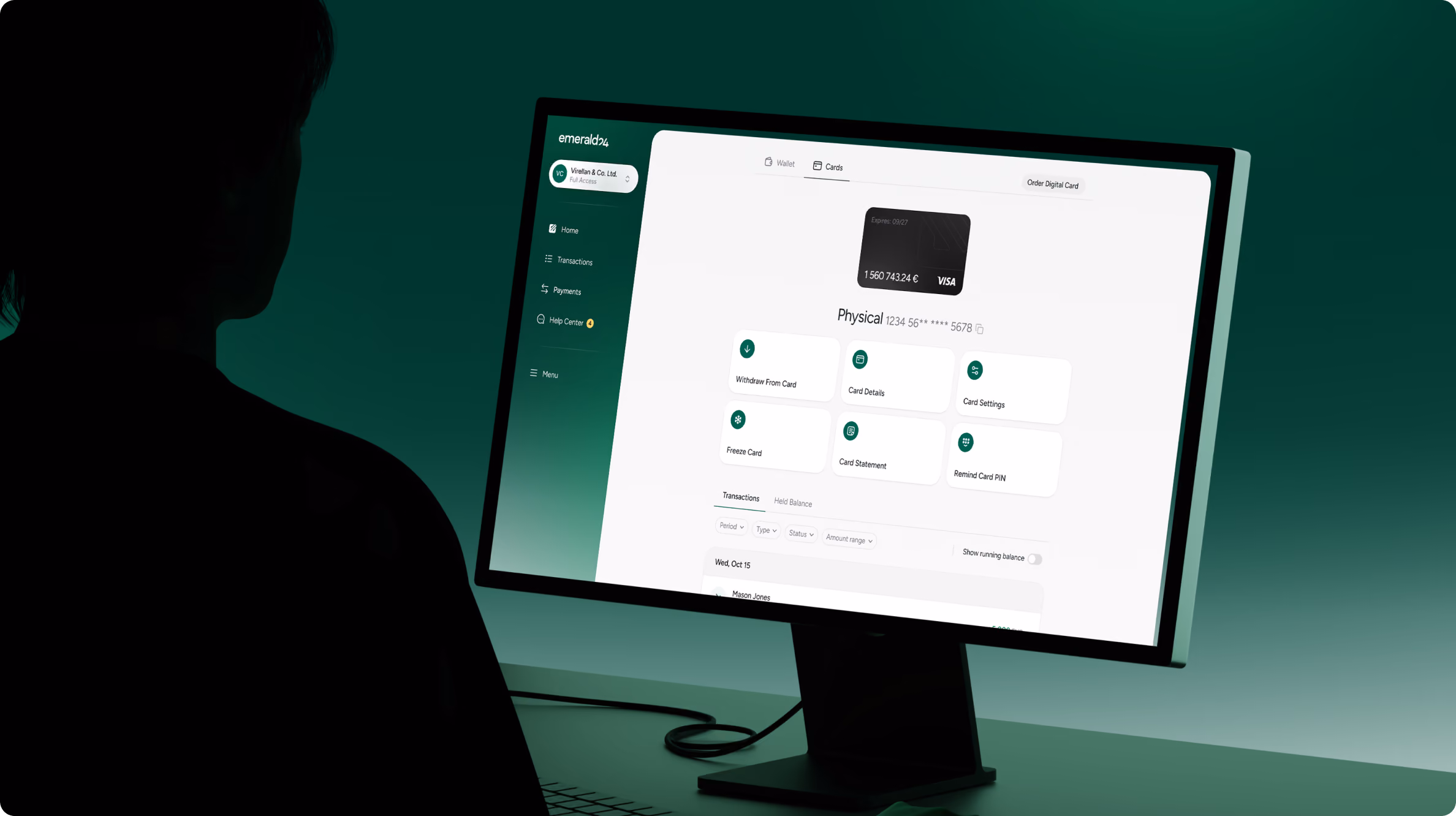 Person in dark silhouette looking at a computer screen displaying a financial dashboard with options for card management, transactions, payments, and help center labeled 'emeraldc'. The screen shows a virtual card image with details and buttons for withdrawing, card details, settings, pausing, statements, and rewards.