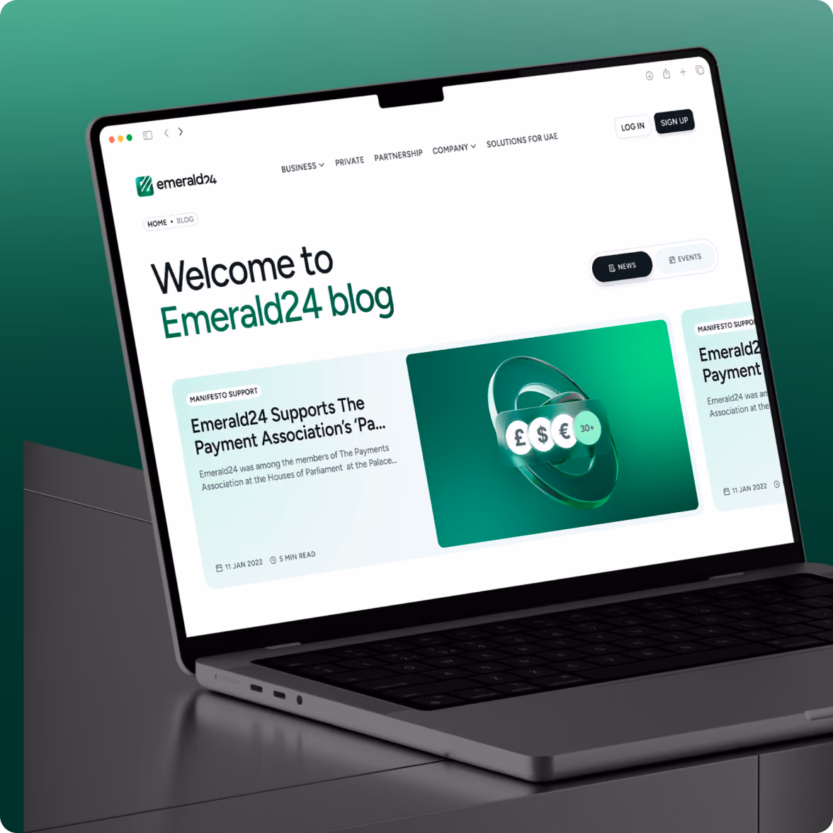 Open laptop on a table displaying the Emerald24 blog homepage with text welcoming visitors and featuring articles about supporting The Payments Association.