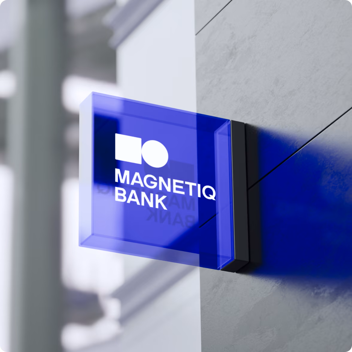 Blue square sign mounted on a building wall with white text and logo reading MAGNETIQ BANK.
