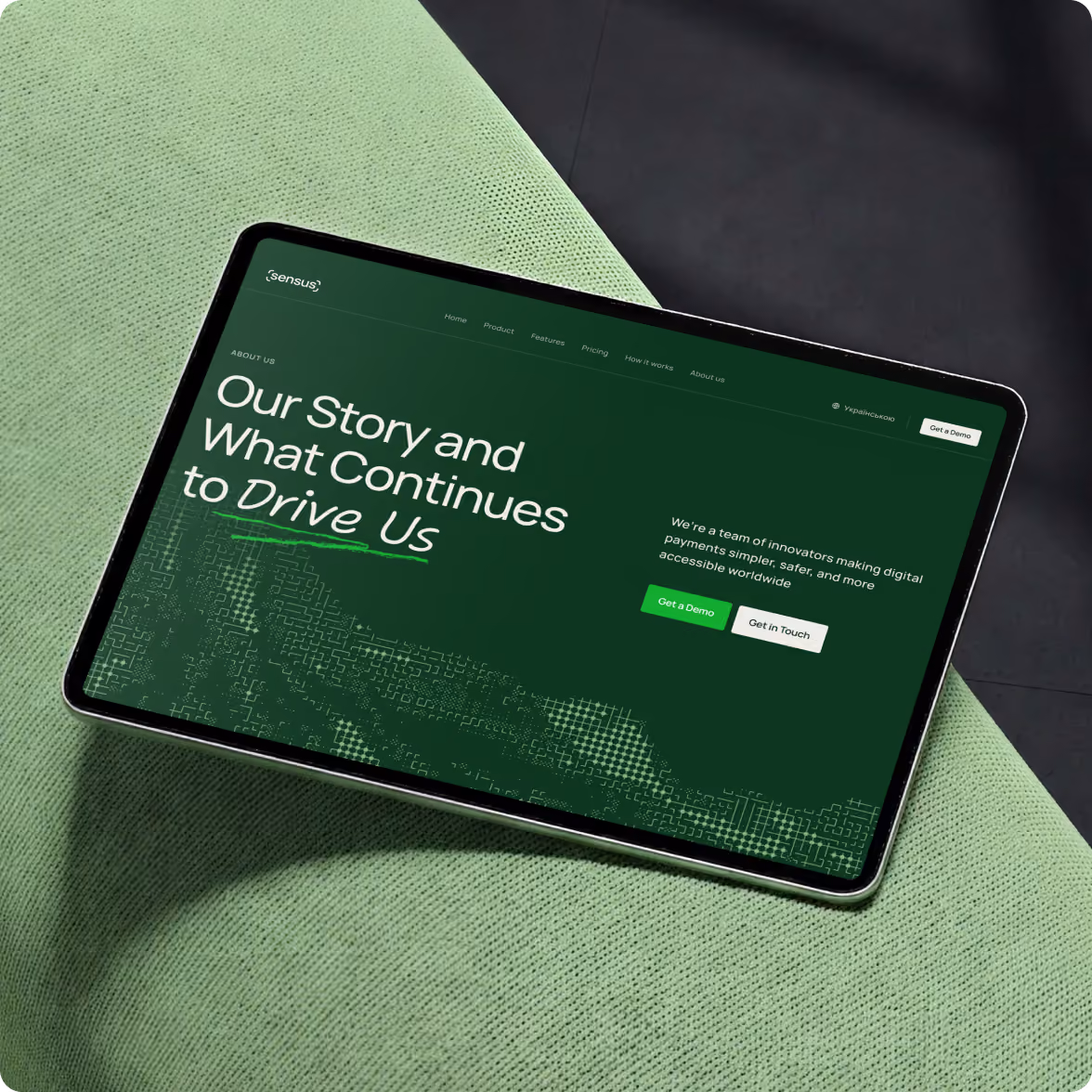 Tablet lying on a light green textured fabric surface displaying a dark green webpage with text about a company's story and digital payment innovation, including buttons for 'Get a Demo' and 'Get in Touch.'