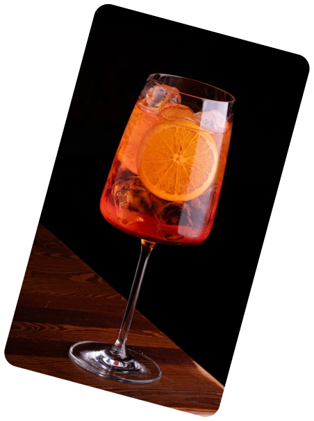 Glass filled with ice cubes topped with a halved passion fruit against a black background.
