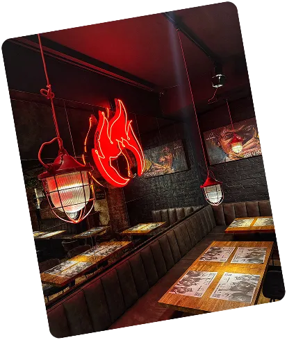 Cozy restaurant booth with hanging lanterns and a red neon flame sign on the dark wall.