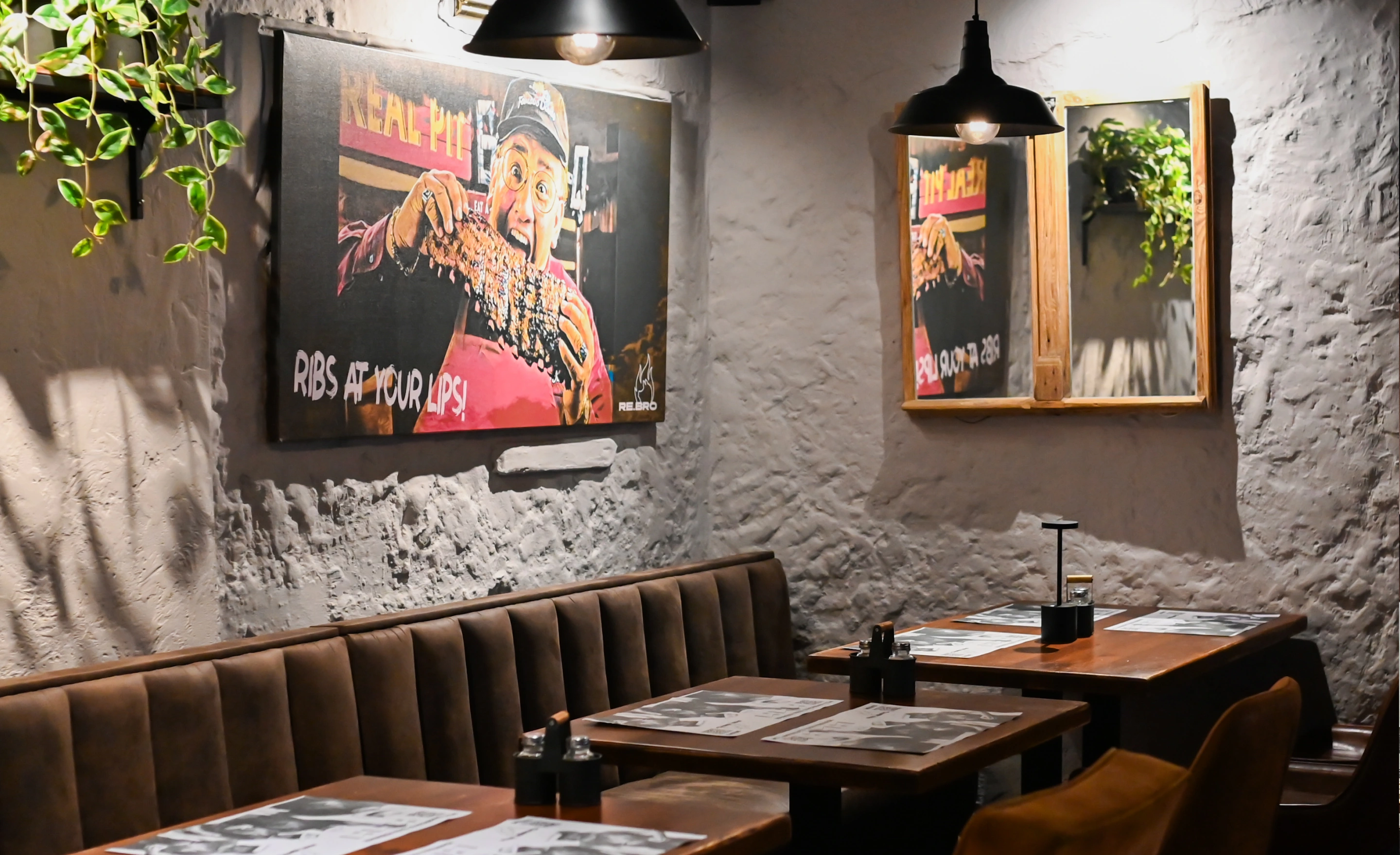 Cozy restaurant corner with brown seating, tables set with placemats, and a wall poster of man eating ribs.