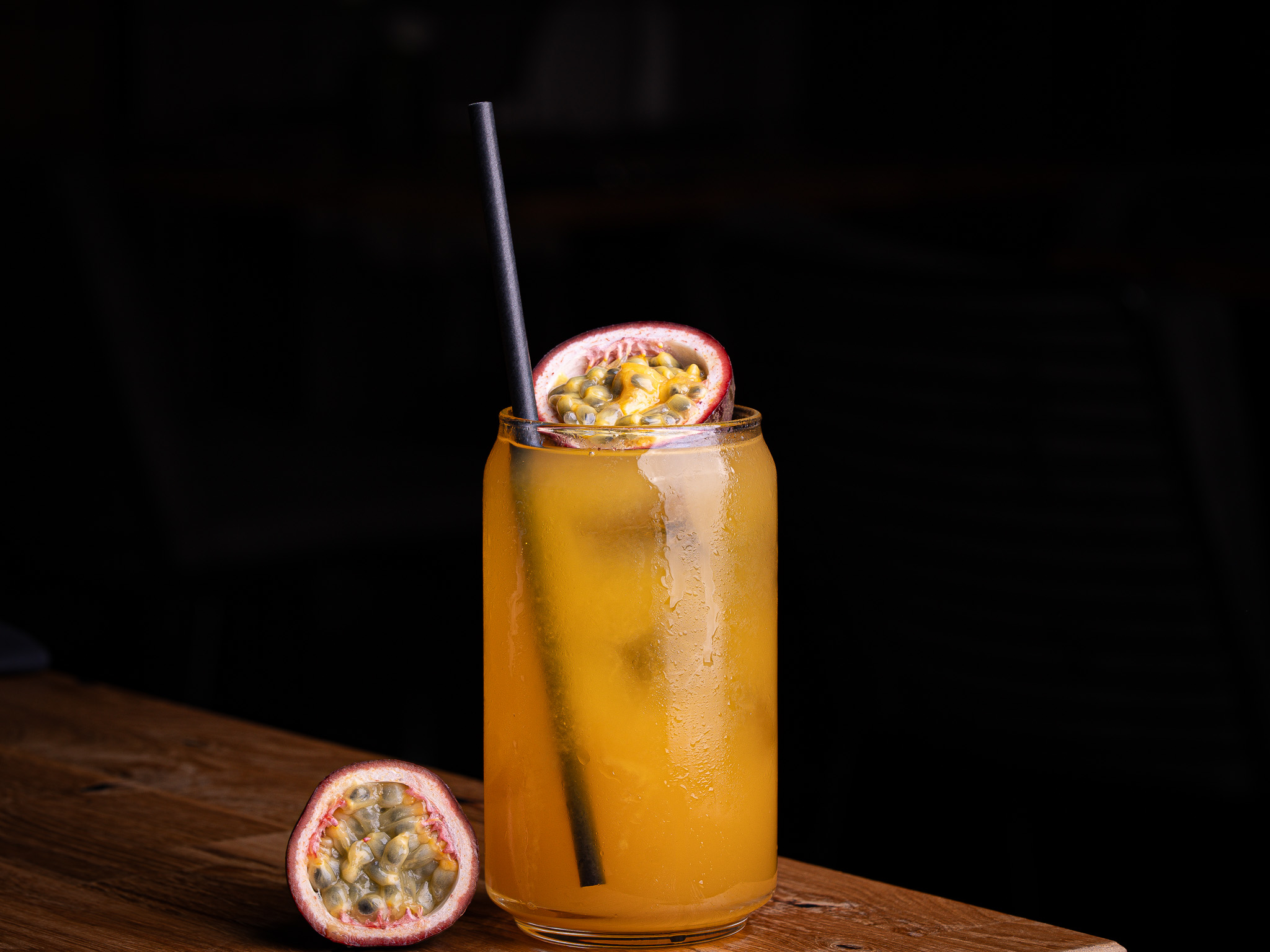 Cocktail in a coupe glass garnished with a lemon twist and mint sprig on a wooden surface.