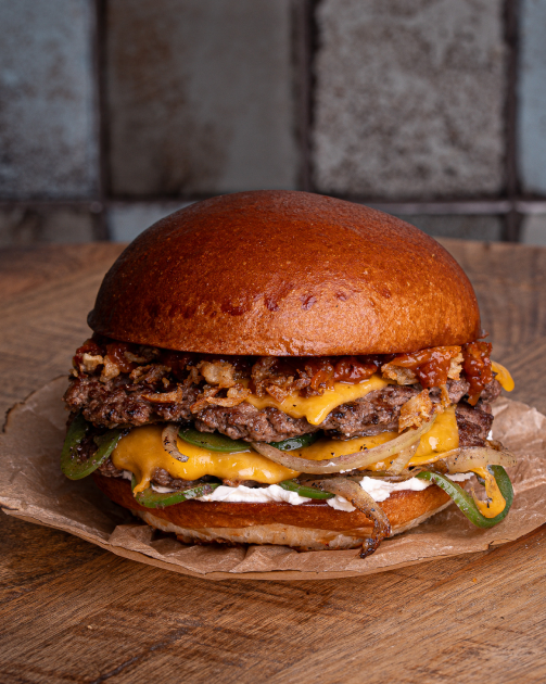 Cheeseburger with grilled mushrooms and onions on a wooden table with dark background.