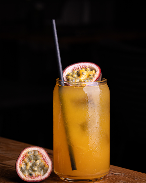 Cocktail in a coupe glass garnished with a lemon twist and fresh mint leaves on a wooden surface.