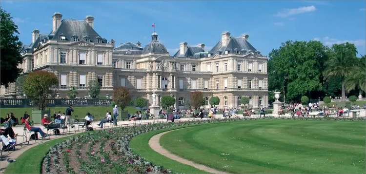 Vue vers le ciel au centre d'une cour carrée entourée de murs ornés de fenêtres gothiques.