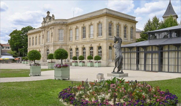 Façade d’un bâtiment avec des fenêtres encadrées de formes géométriques rouges répétées.
