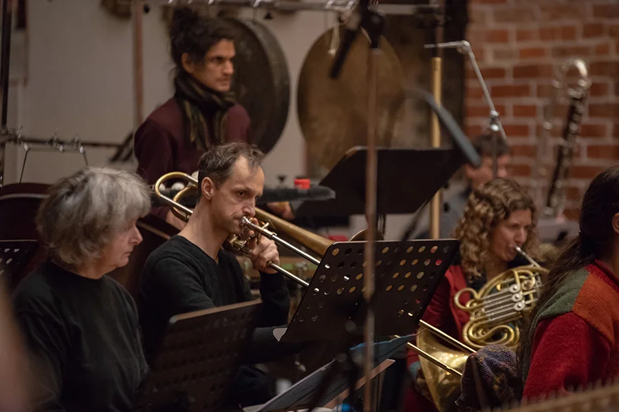 Musiker spielen Blasinstrumente in einem Orchester mit Posaune und Horn im Fokus.