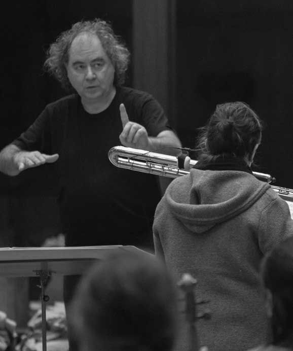 Dirigent dirigiert Musikerin mit Posaune in schwarz-weißem Orchesterprobenbild.