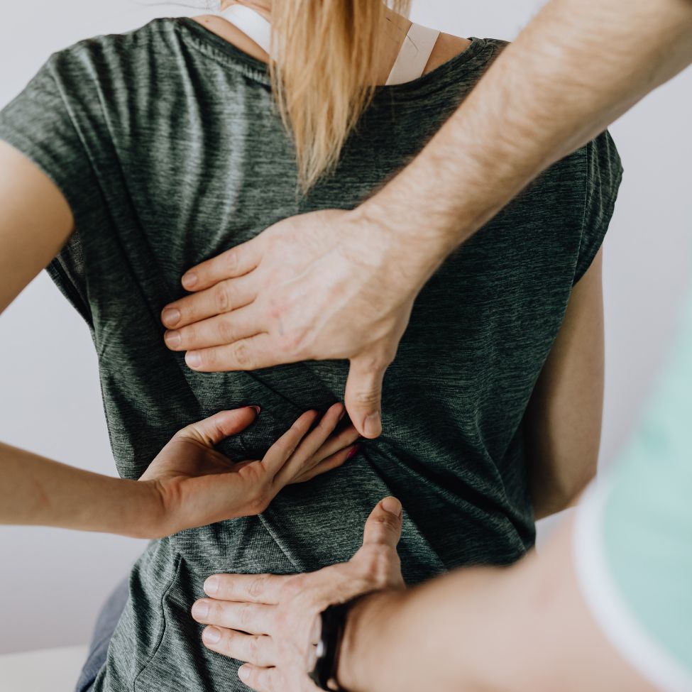 Therapist's hands pressing on a woman's back during a chiropractic or physical therapy session.