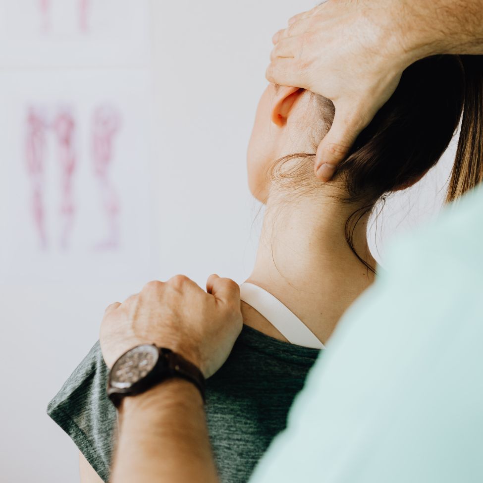 Chiropractor adjusting a woman's neck and shoulder in a clinical setting.