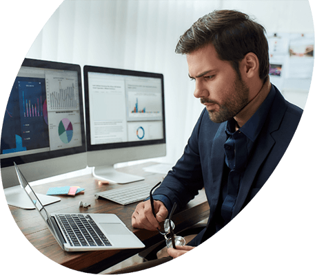 Professional reviewing financial charts on multiple monitors