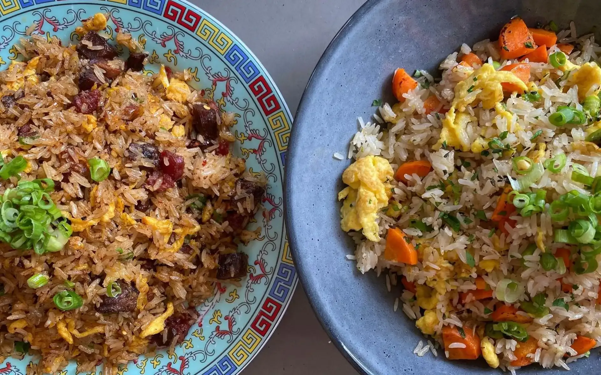 Two plates of fried rice dishes, one with dark meat and egg, the other with carrots, egg, and green onions.