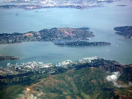 Aerial view of a coastal area with islands, water, docks, and urban development.