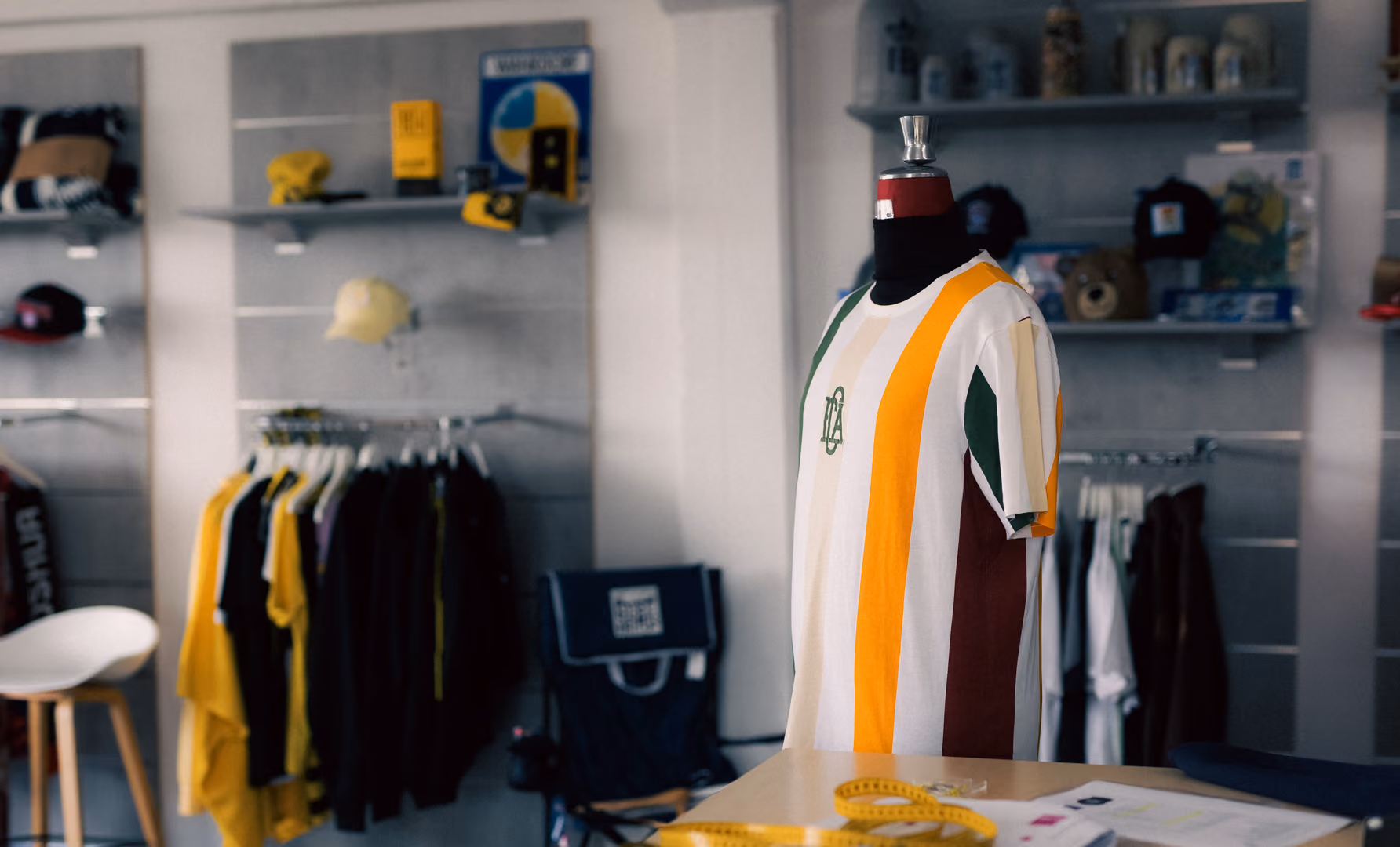 Striped yellow, white, green, and brown tee on a mannequin in a clothing store.