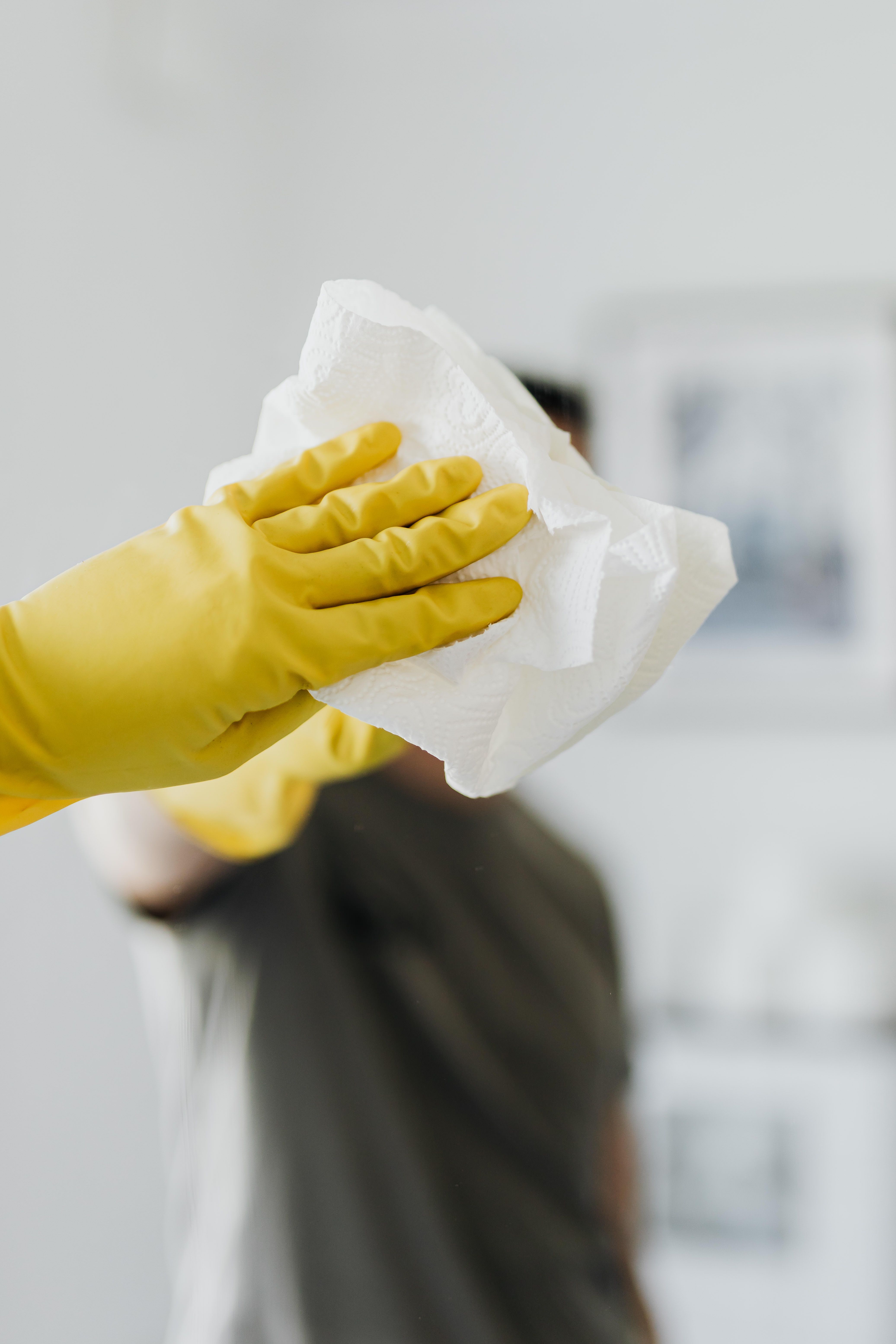 A person cleaning a mirror with a white towel