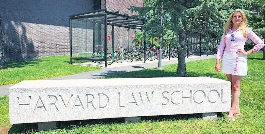 Group of five people including children and adults conversing on a sunny sidewalk near a large tree in a suburban neighborhood.