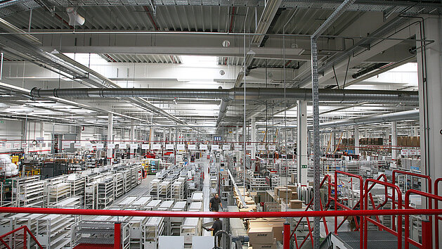 Vue d'un grand entrepôt industriel avec rayonnages et palettes organisés sous plafond métallique.