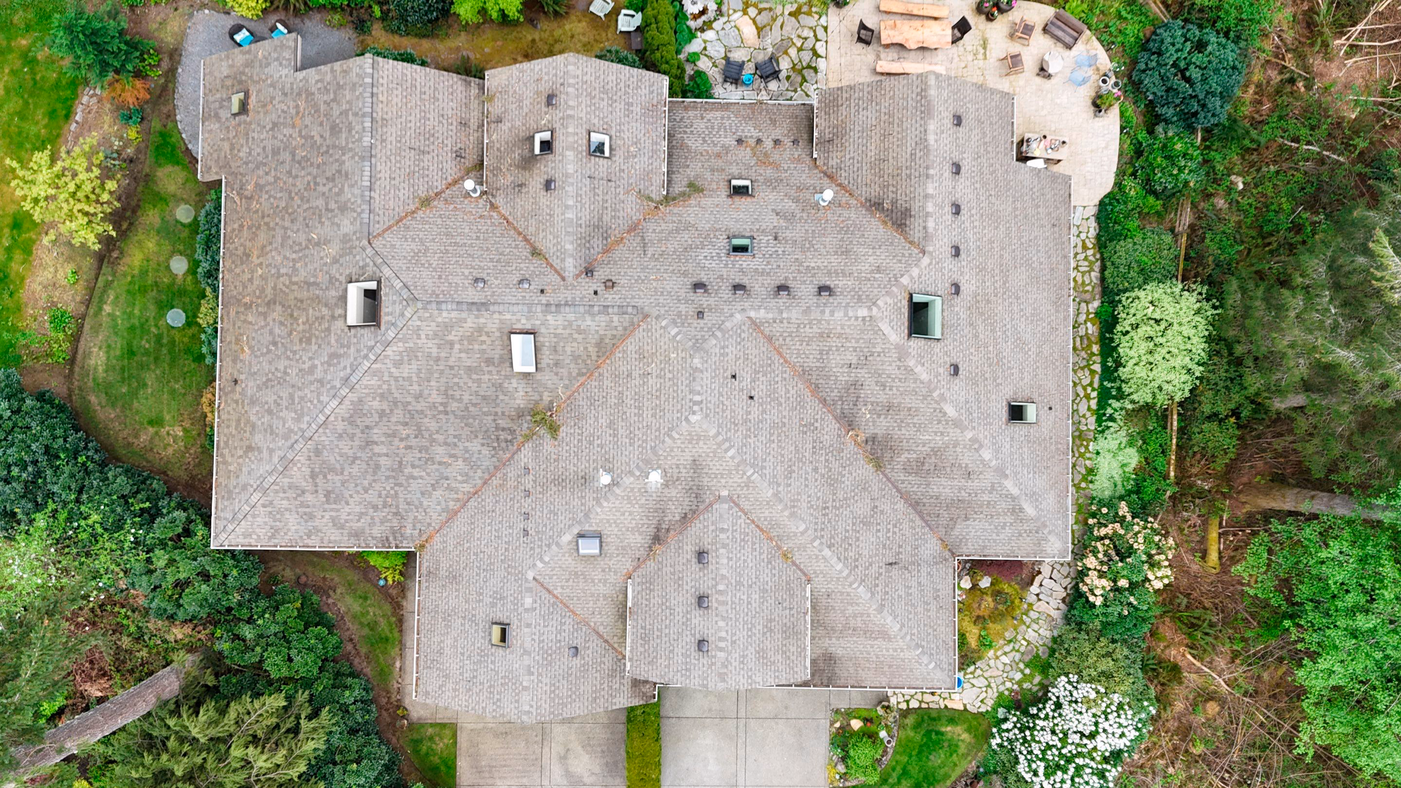 Aerial view of a residential roof replacement project with gray shingles and surrounding neighborhood.