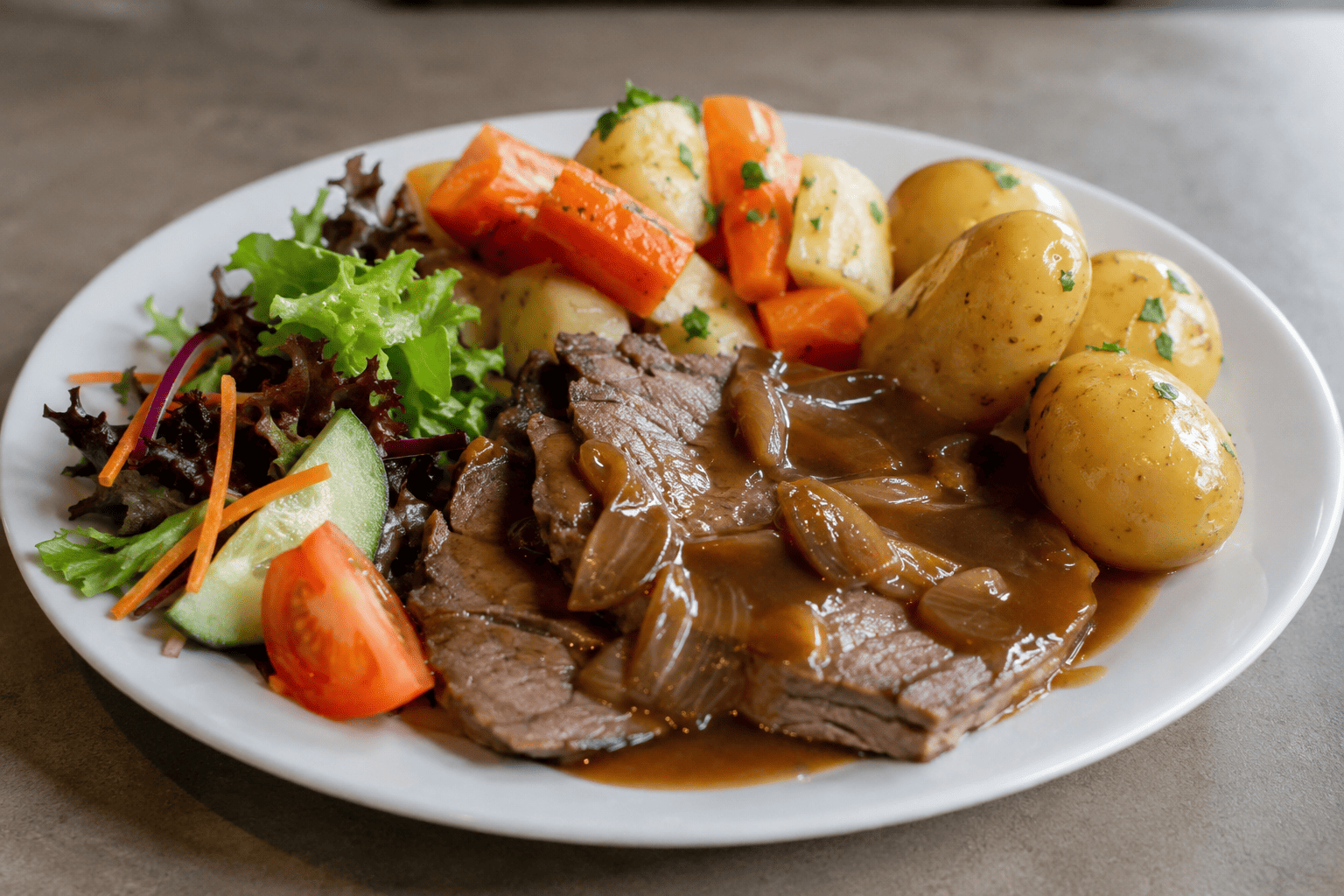 Plate with sliced roast beef in onion gravy, new potatoes, carrots, parsnips, and mixed salad with tomato.