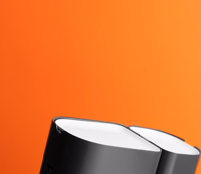Close-up of black and white modern speakers against an orange background.