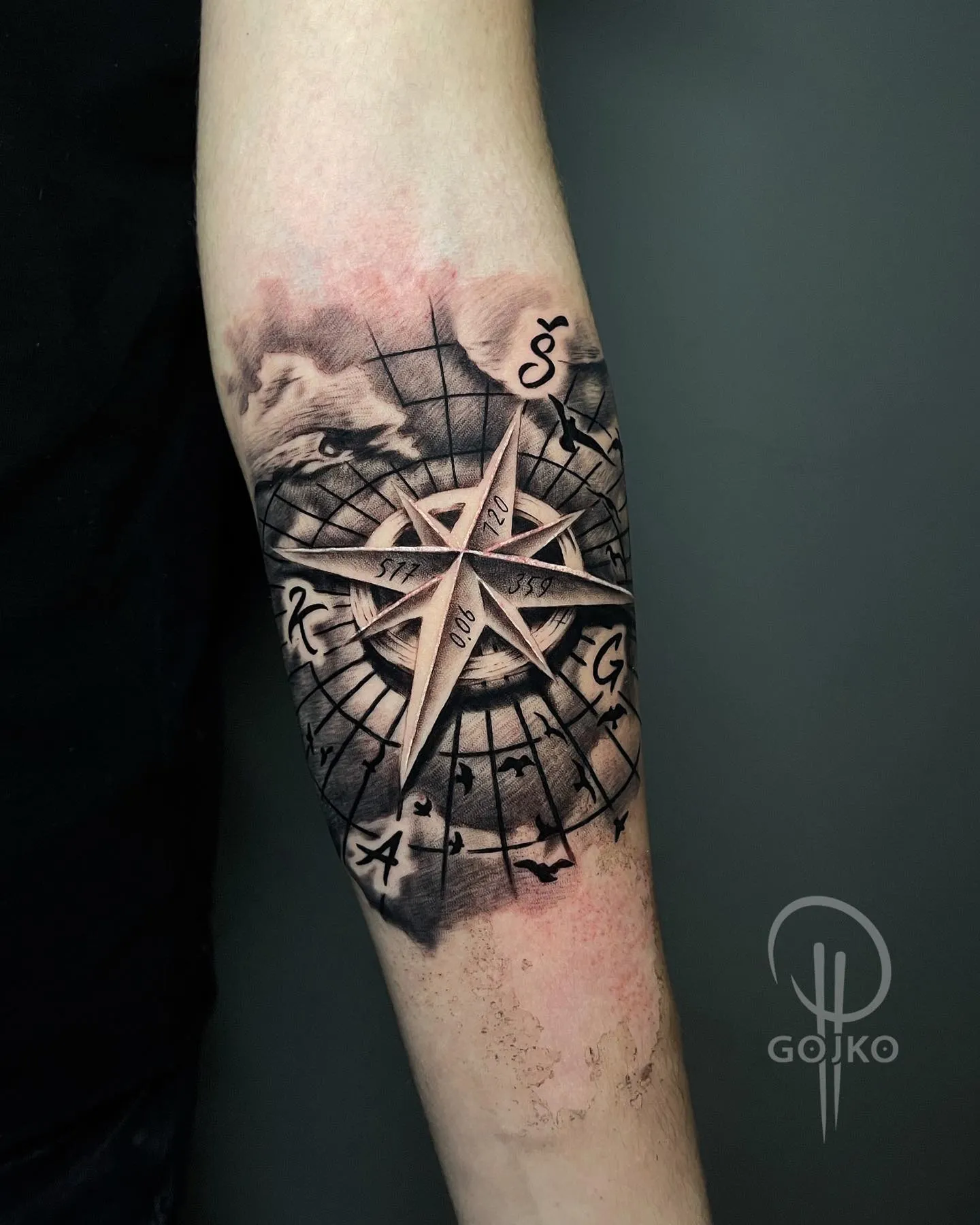 Realistisches Black and Grey Kompass Tattoo am Unterarm – 3D-Kompassrose mit Initialen, Vögeln und Wolken, von Gojko, INK SOCIETY