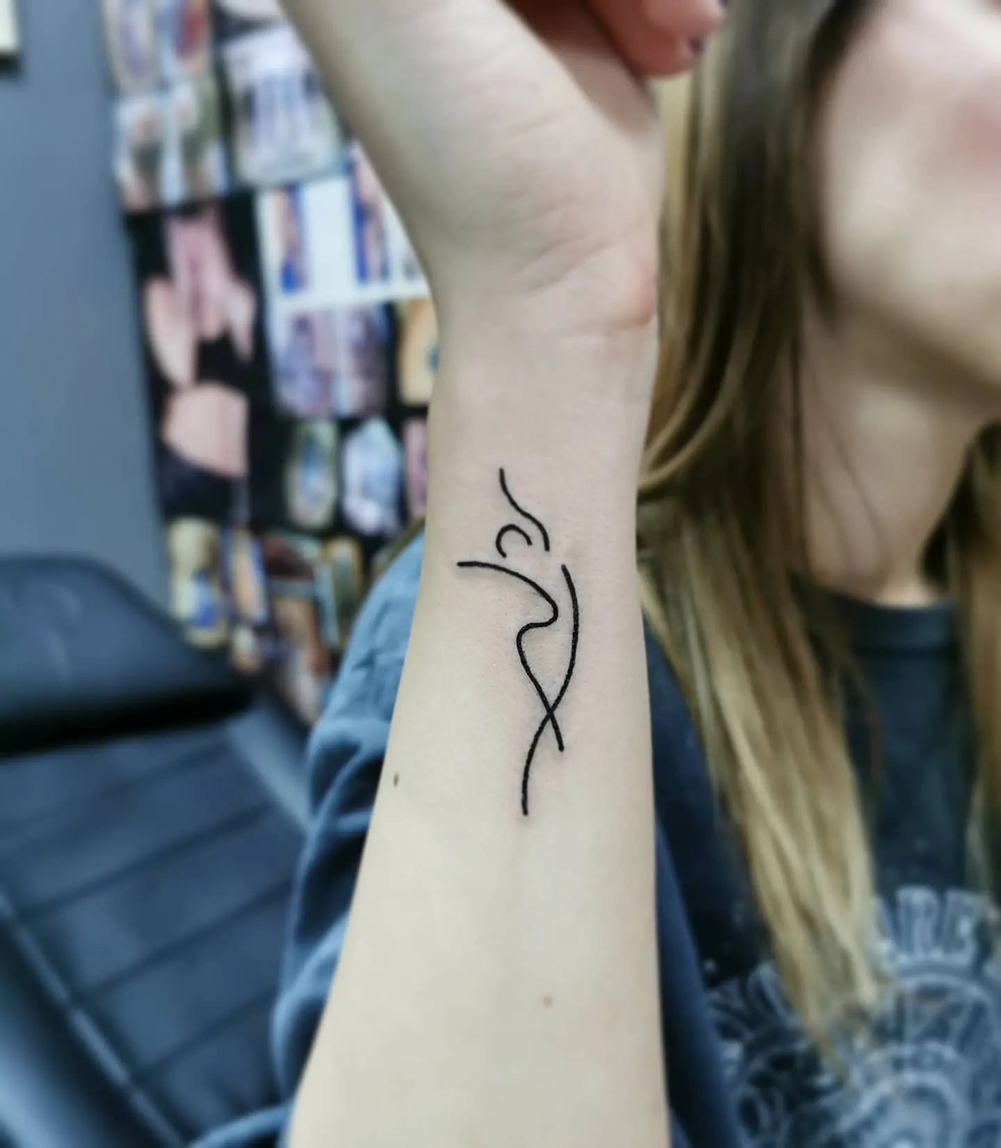 Minimalistisches Linien Tattoo am Handgelenk – abstrakte tanzende Figur in schwarzer Fine Line, INK SOCIETY