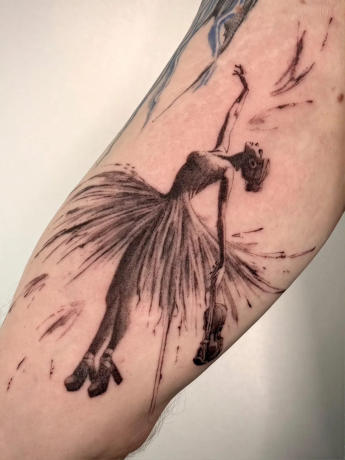 Black and Grey Tänzerin Tattoo am Arm – Frau mit wehendem Kleid und Geige im Sketch-Stil mit Pinselstrichen, von Lara, INK SOCIETY
