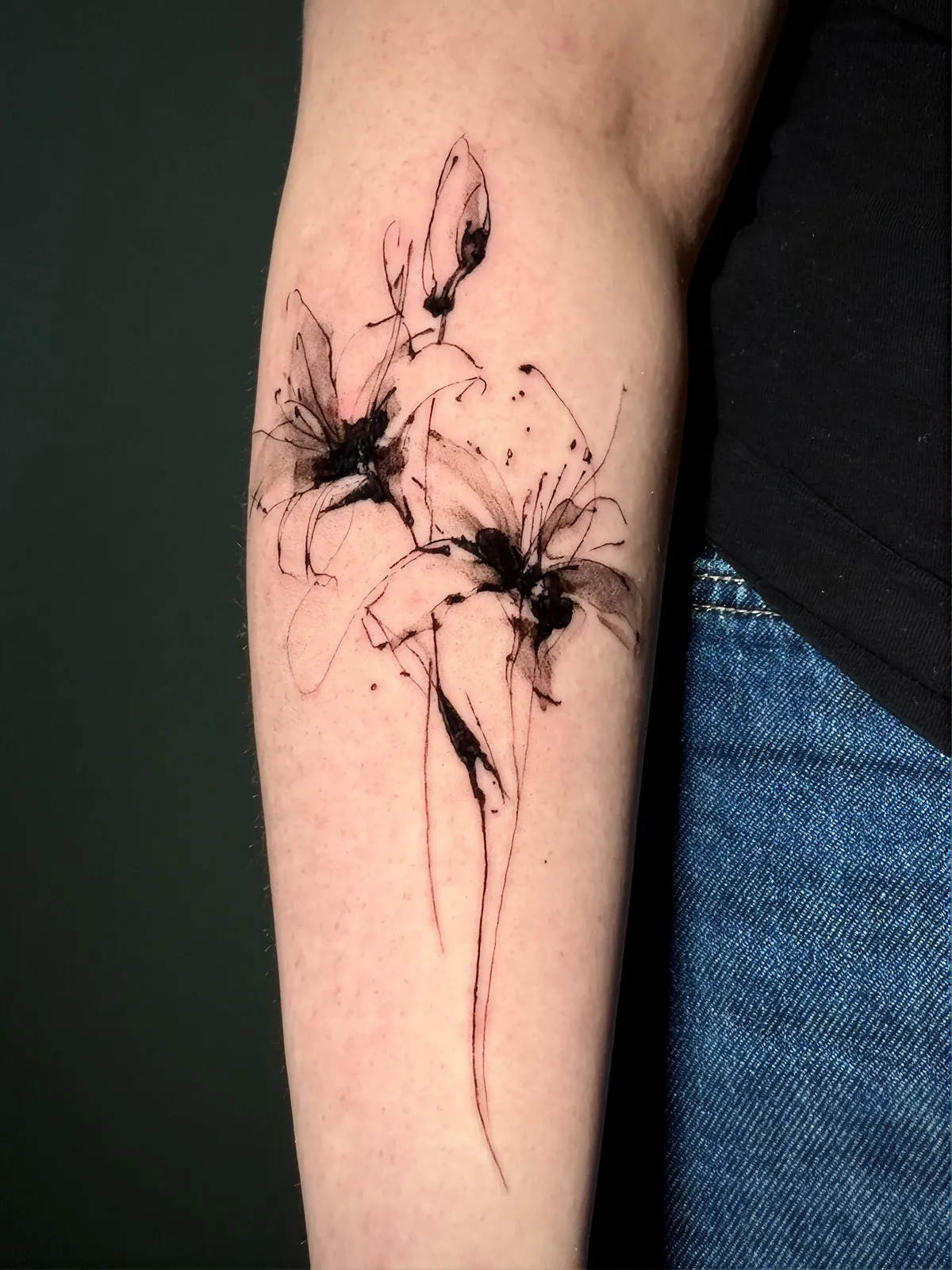 Lilien Tattoo am Unterarm im Sketch-Stil – zwei Lilienblüten mit Knospe in schwarzer Tusche und feinen Linien, von Lara, INK SOCIETY