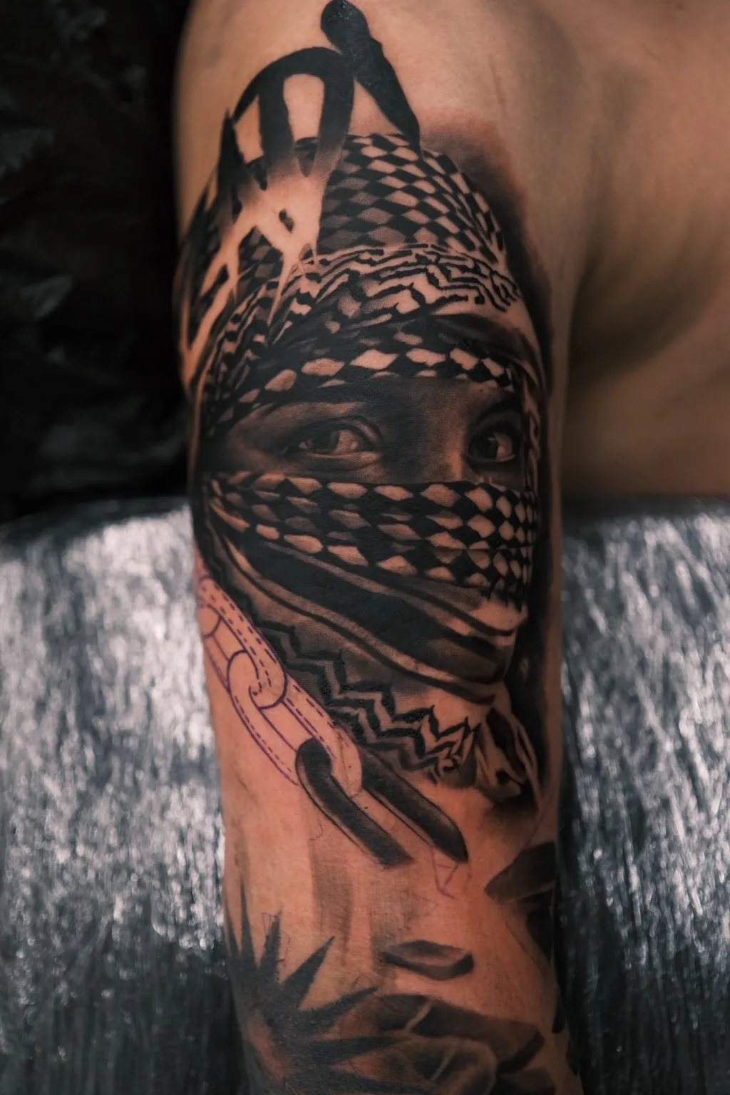 Black & Grey Realistic Tattoo am Arm: Gesicht mit Kufiya, nur die Augen frei, gestochen von Gojko bei INK SOCIETY in Kiel