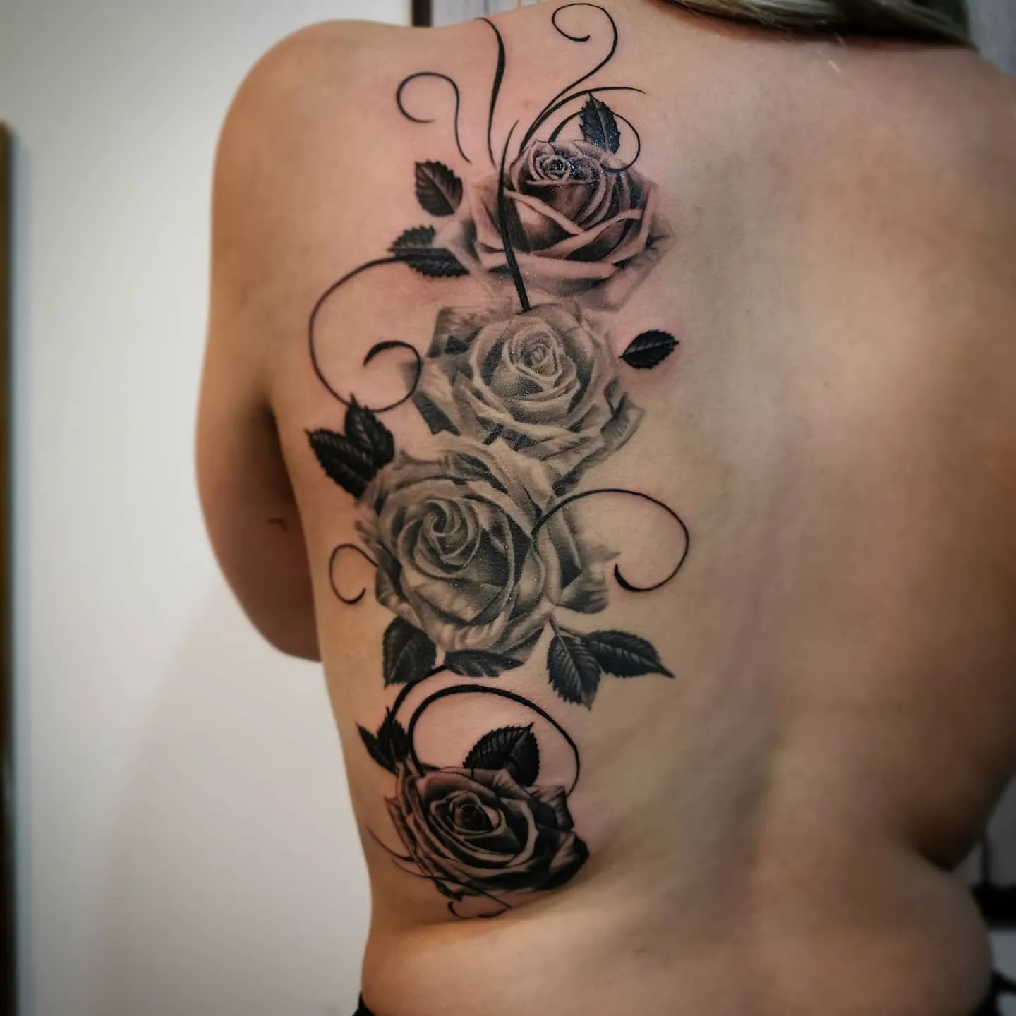 Realistisches Black and Grey Rosen Tattoo am Rücken – vier Rosen mit Blättern und verspielten Ranken entlang der Schulter, INK SOCIETY