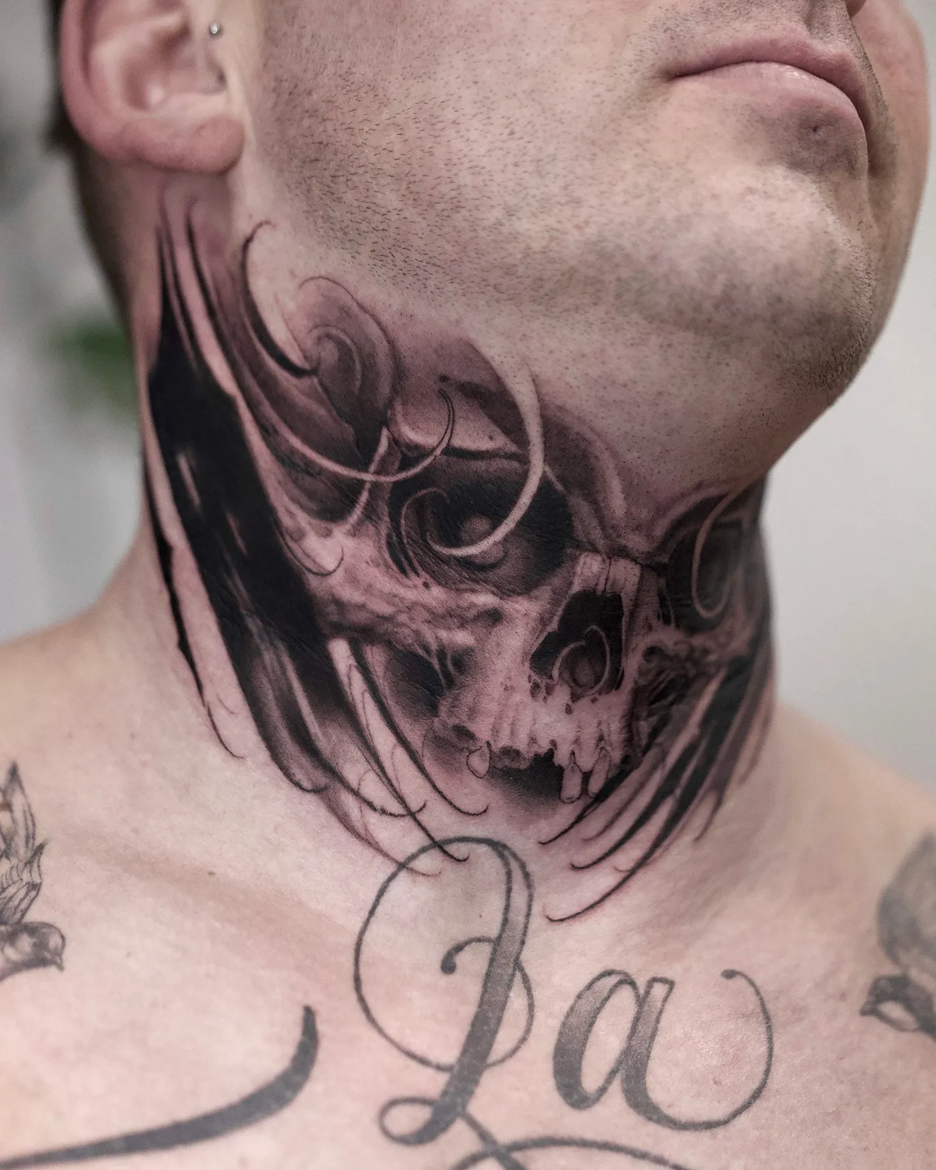 Totenkopf-Tattoo am Hals in Schwarz und Grau mit dunklen, fließenden Formen, gestochen von Asti bei INK SOCIETY in Kiel