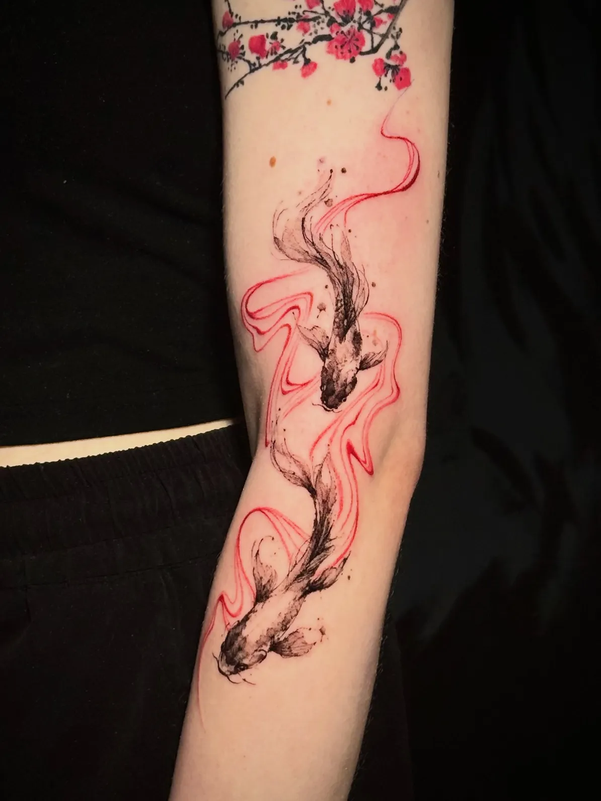 Koi Tattoo am Arm im Tuschestil – zwei Koi-Fische mit roten Wellenlinien und Kirschblüten, von Lara, INK SOCIETY