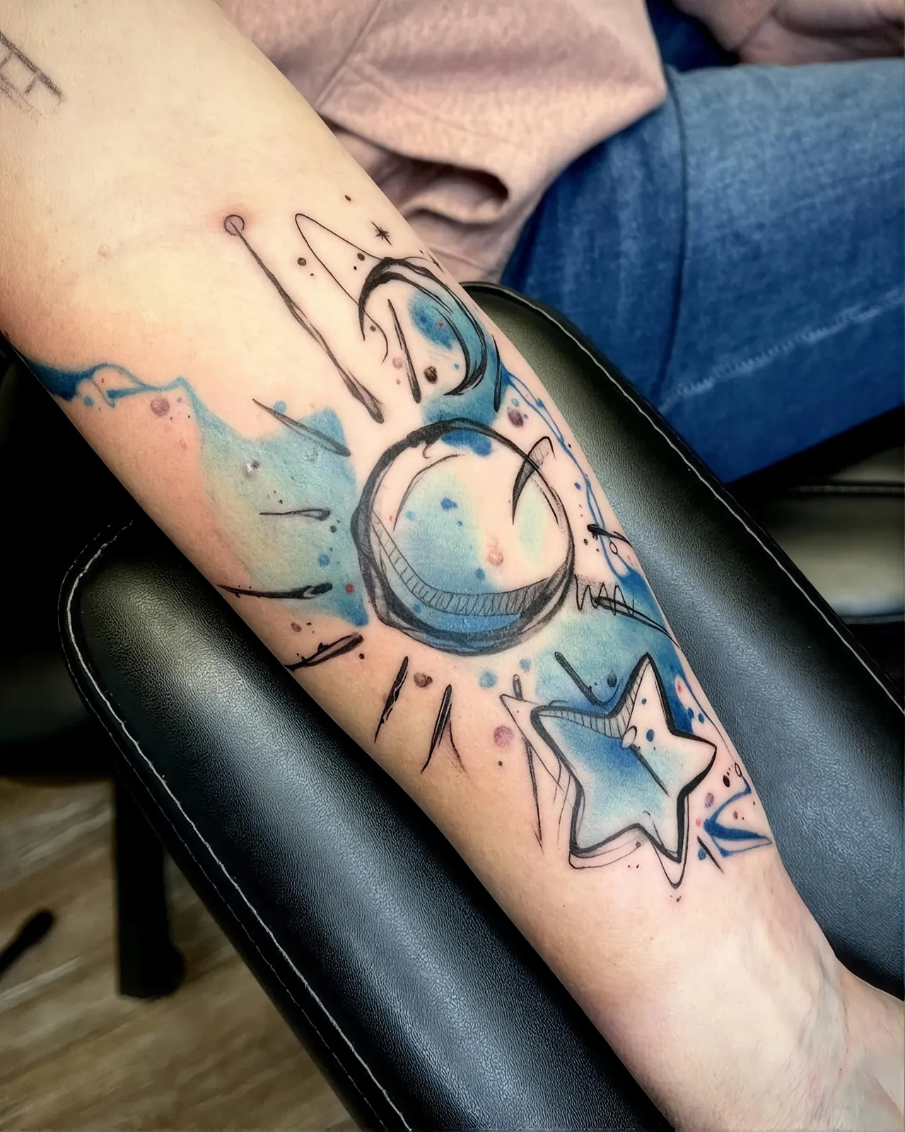 Watercolor Tattoo am Unterarm – Mond, Planet und Stern im Sketch-Stil mit blauen Farbflächen, von Lara, INK SOCIETY