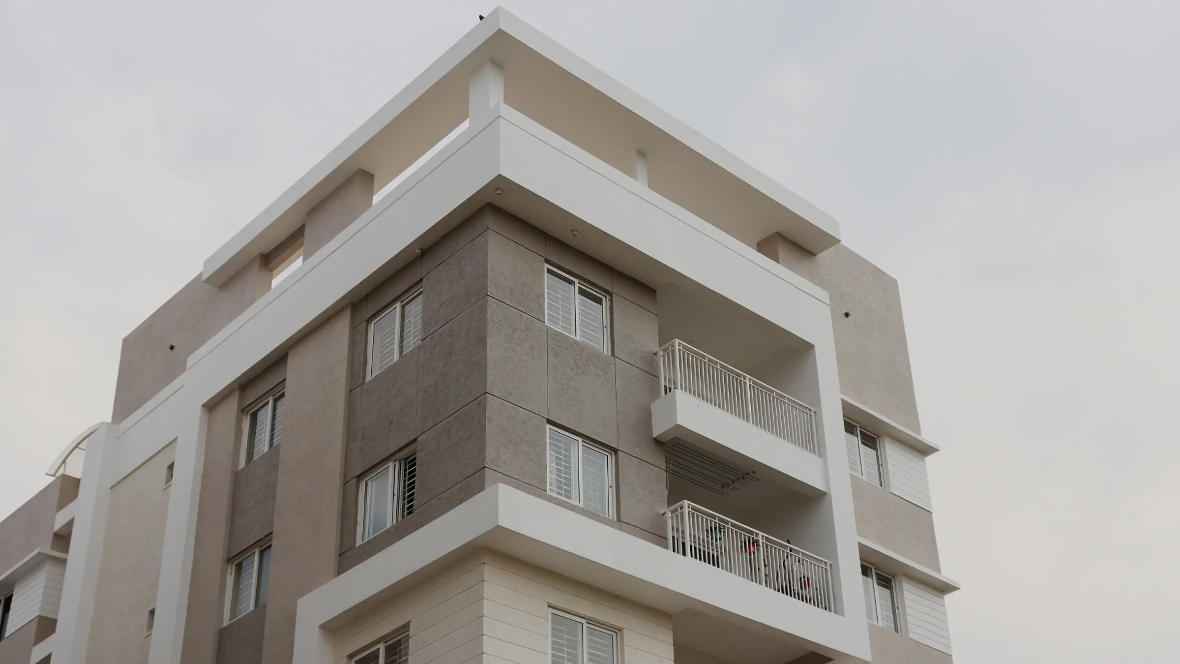 Moderner mehrstöckiger Wohnblock mit grauen und weißen Fassaden und Balkonen.