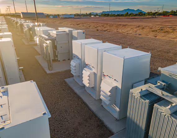 Rows of EPC electrical transformers installed outdoors on concrete pads under a setting sun.