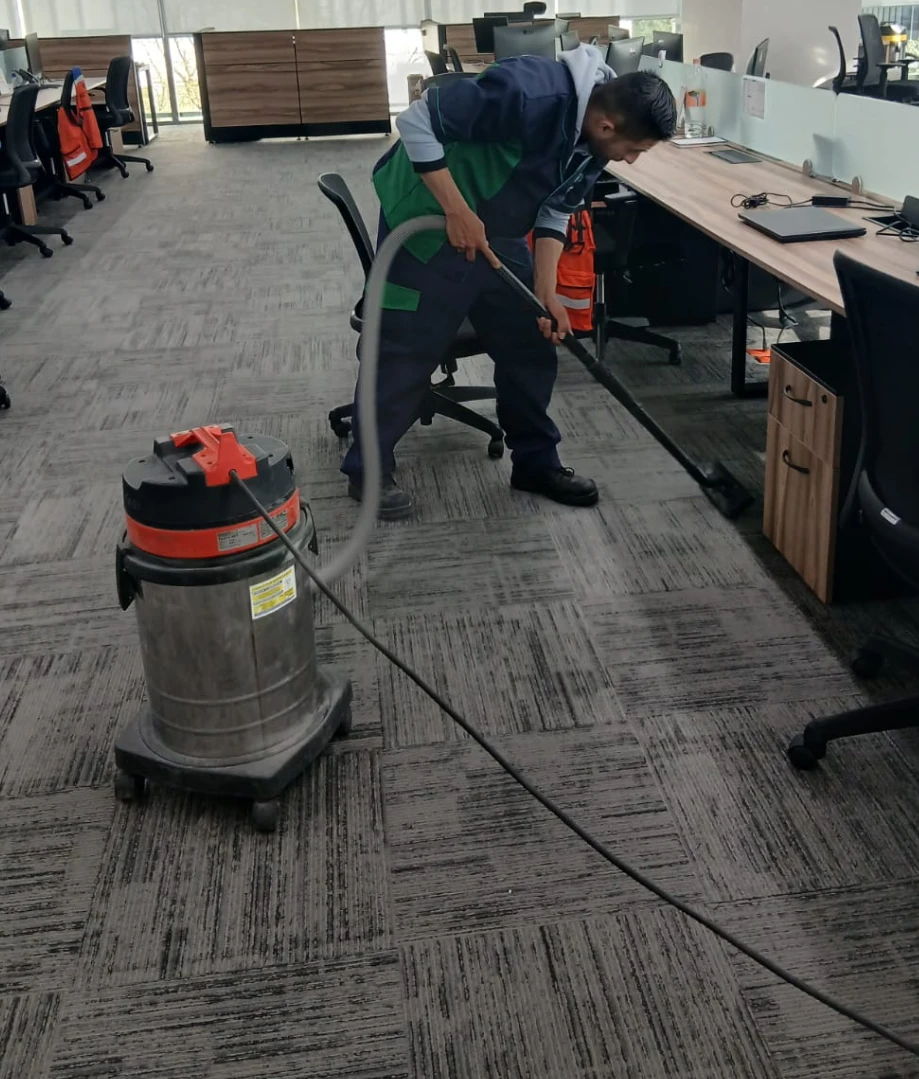 Auxiliar de limpieza aspirando la alfombra