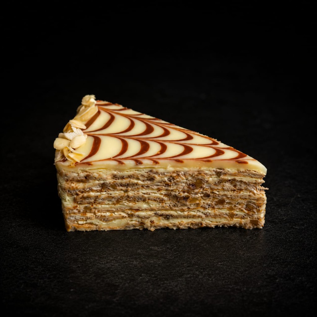 Stück Esterházy-Torte mit Schokoladenmuster und Mandeln.