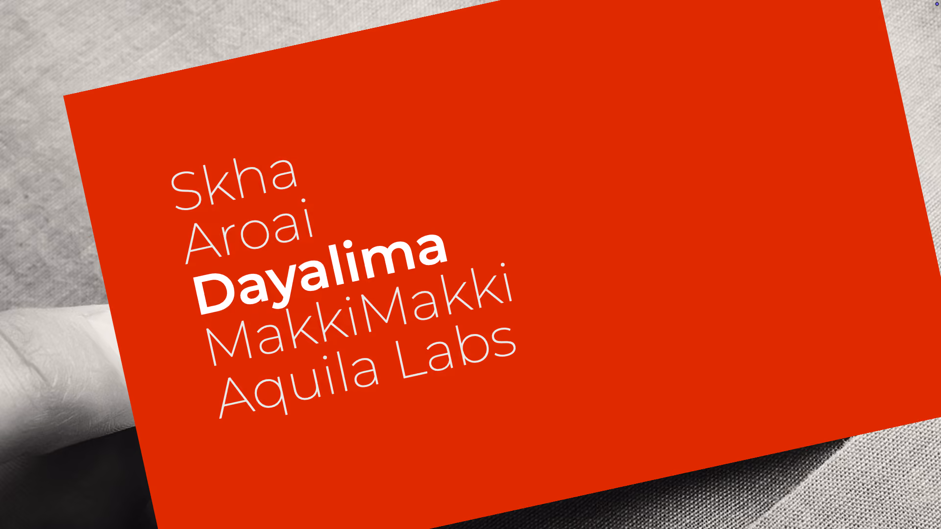 A hand holding a red card with the white text: 'Skha Aroai Dayalima Makki Makki Aquila Labs,' with 'Dayalima' in bold.
