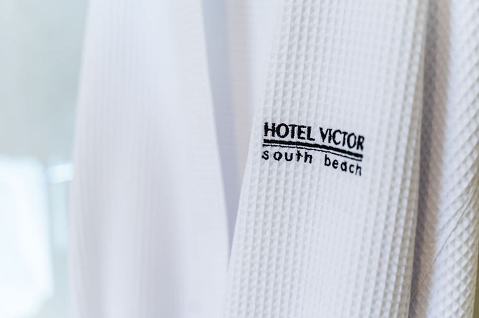 Close-up of a white textured hotel robe embroidered with Hotel Victor South Beach logo.