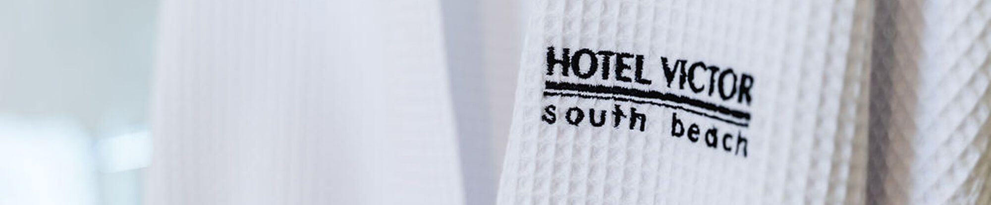Close-up of a white textured fabric with 'HOTEL VICTOR south beach' embroidered in black.