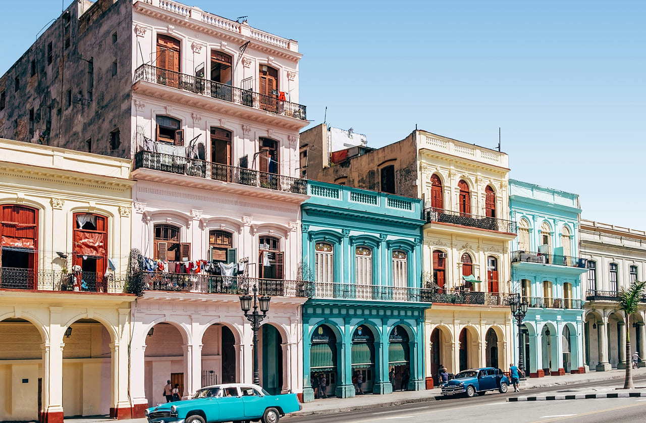 Colorful colonial buildings with balconies and classic cars on the street in Havana, Cuba.
