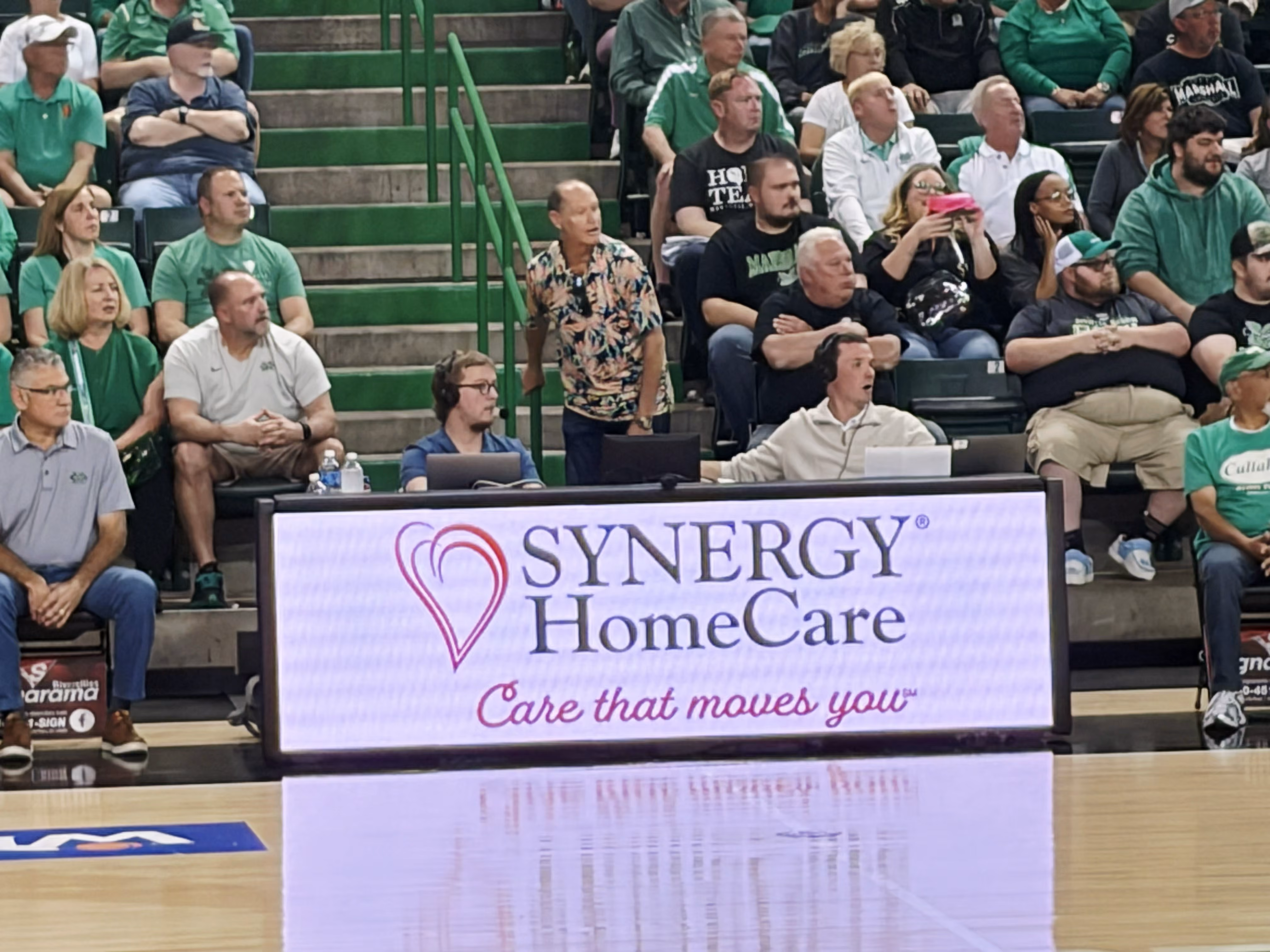 Image of a the SYNERGY® HomeCare logo displayed on an LED screen at a sporting event.